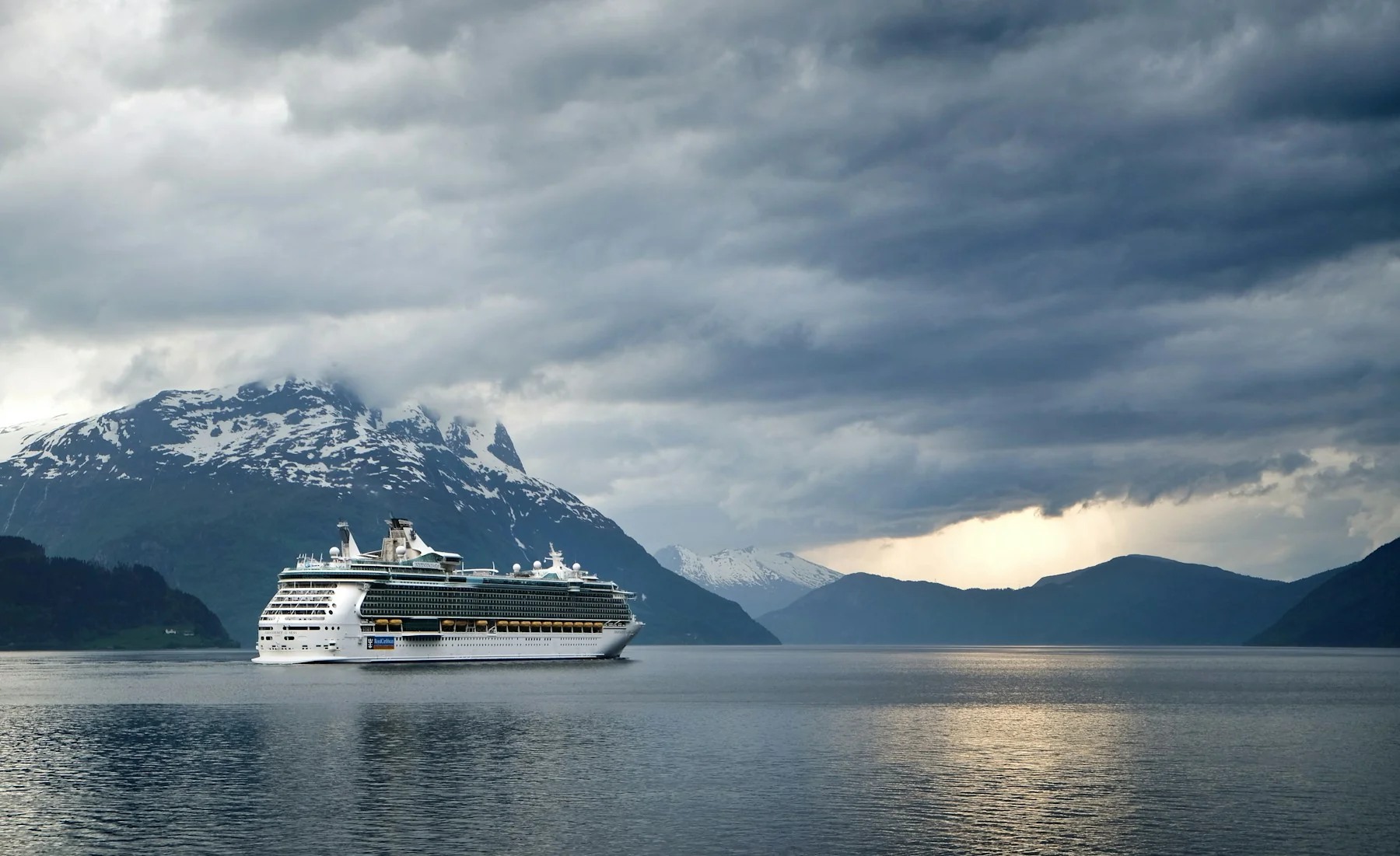 Ocean cruise ship on calm water in Norway’s Nordfjord, surrounded by mountains