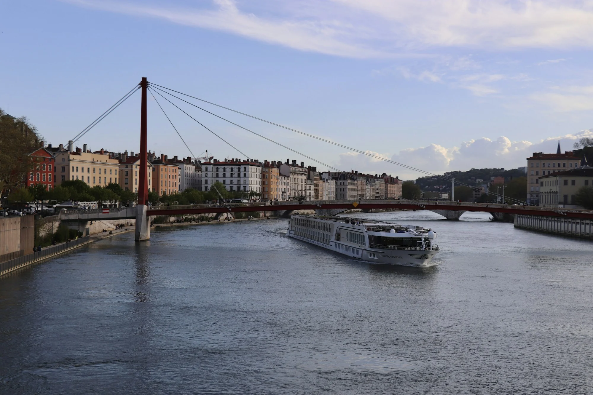 River cruise ship on the Saône in Lyon, with a red footbridge and riverside buildings